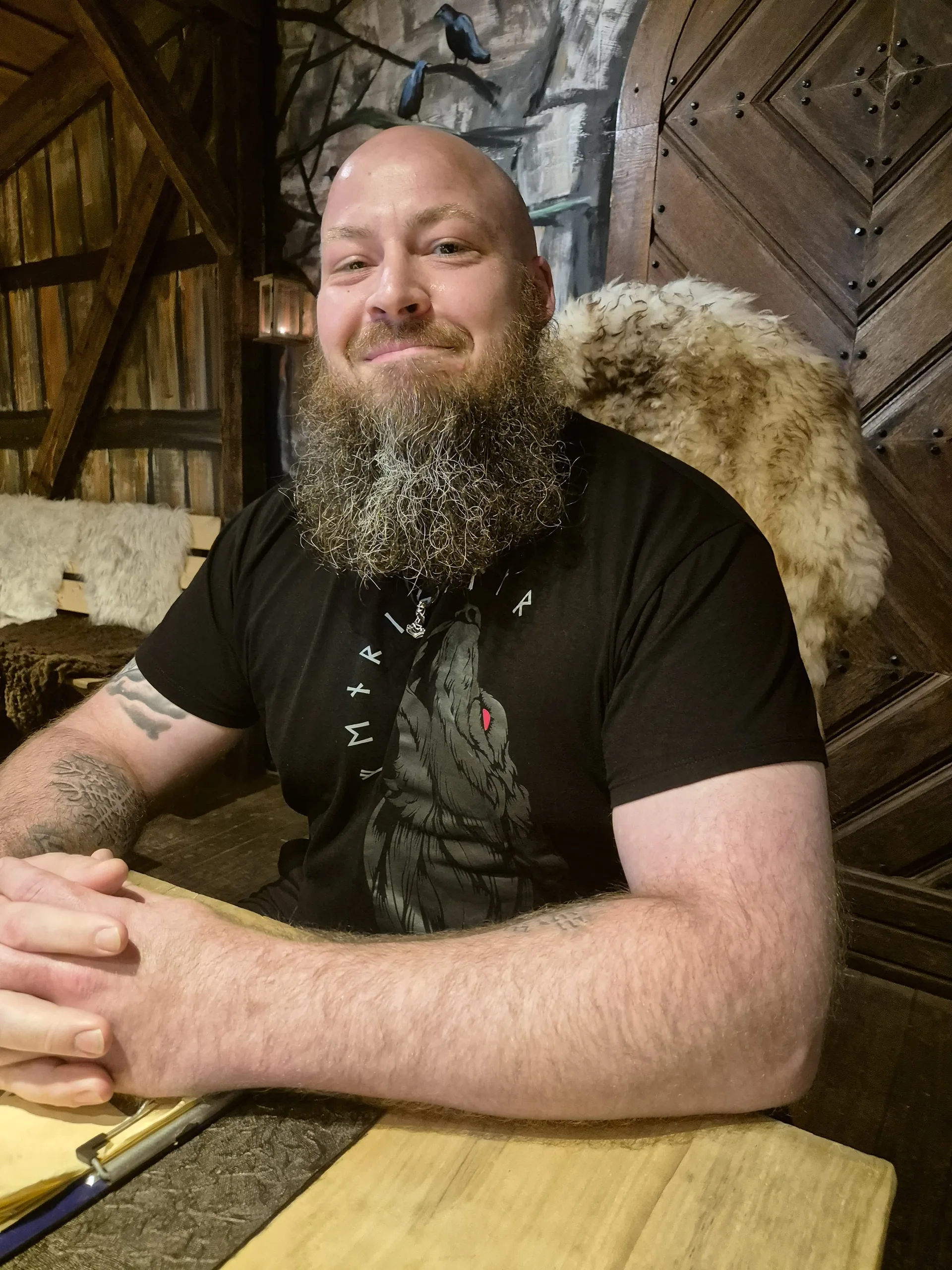 Mann mit hellem Vollbart in einer hölzernen Met-Halle, North Legendary Fenris-Wolfsrune-Shirt