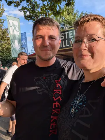 Paar auf einem Wikinger-Festival, beide in North Legendary Shirts – Mann im Berserker, Frau im Vegvisir-Walhalla-Motiv