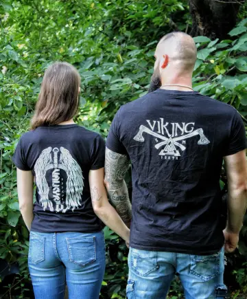 Paar von hinten Hand in Hand im Wald, Rückenmotive: Valkyria-Flügel bei der Frau, Wikinger-Äxte beim Mann